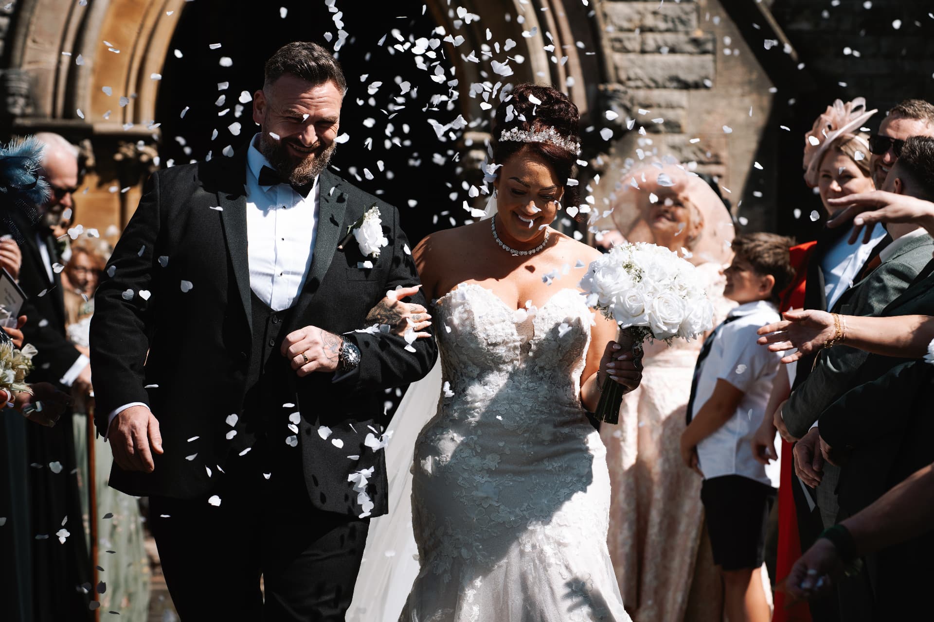 Newlyweds walking through a shower of confetti outside the church