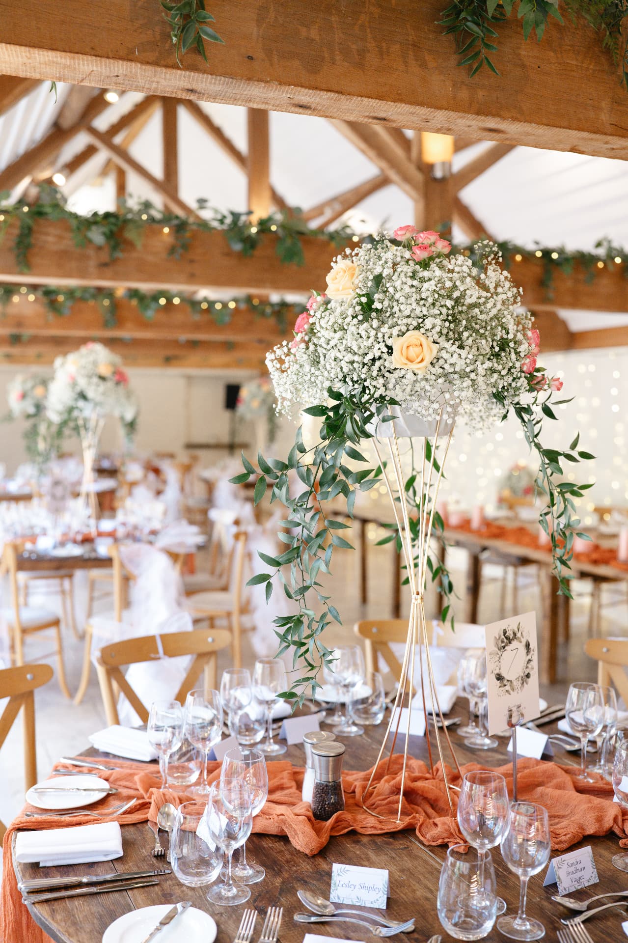 Flower-filled wedding breakfast tables inside a timber barn