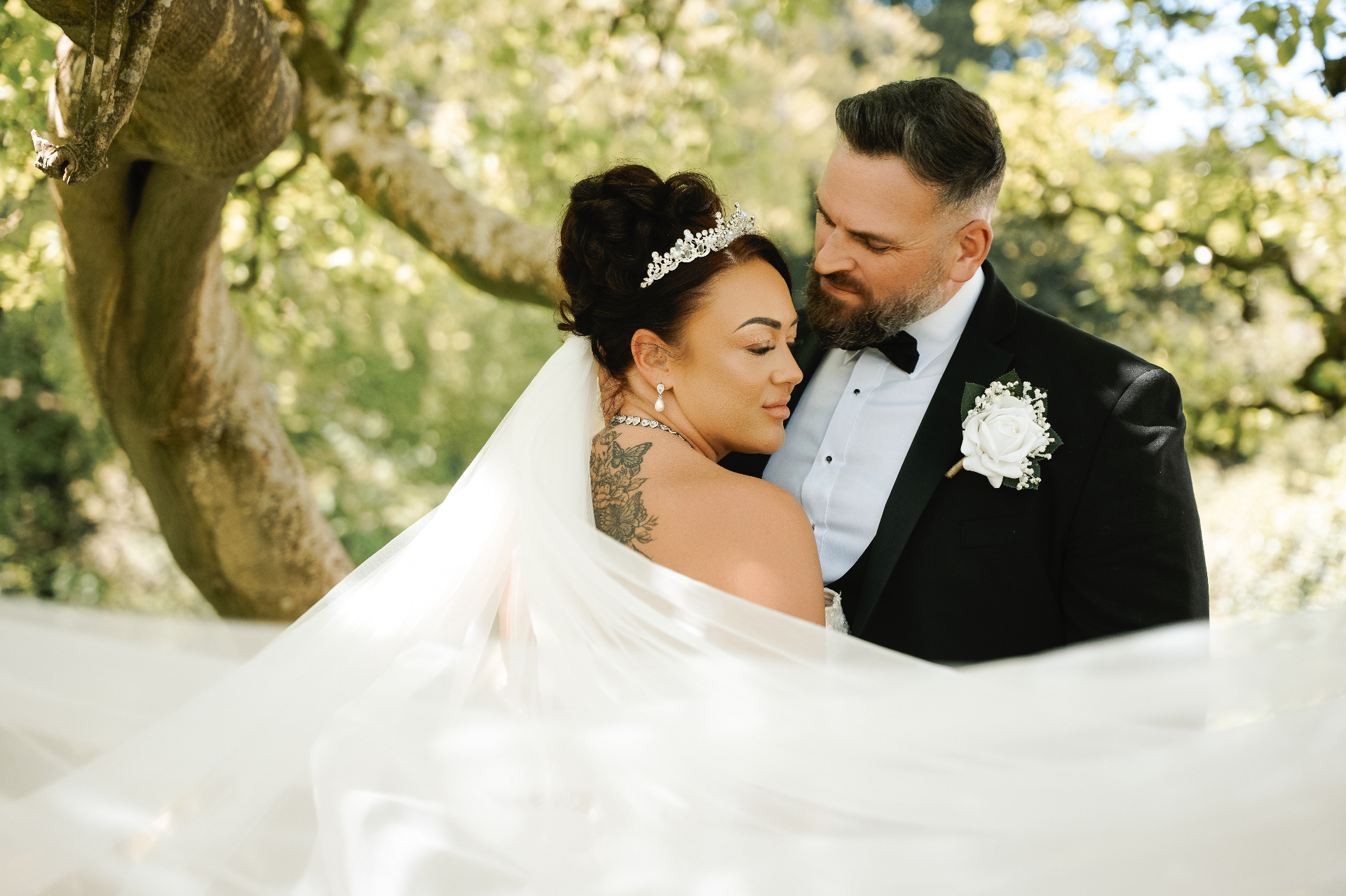 Bride and groom in a quiet embrace beneath an old tree
