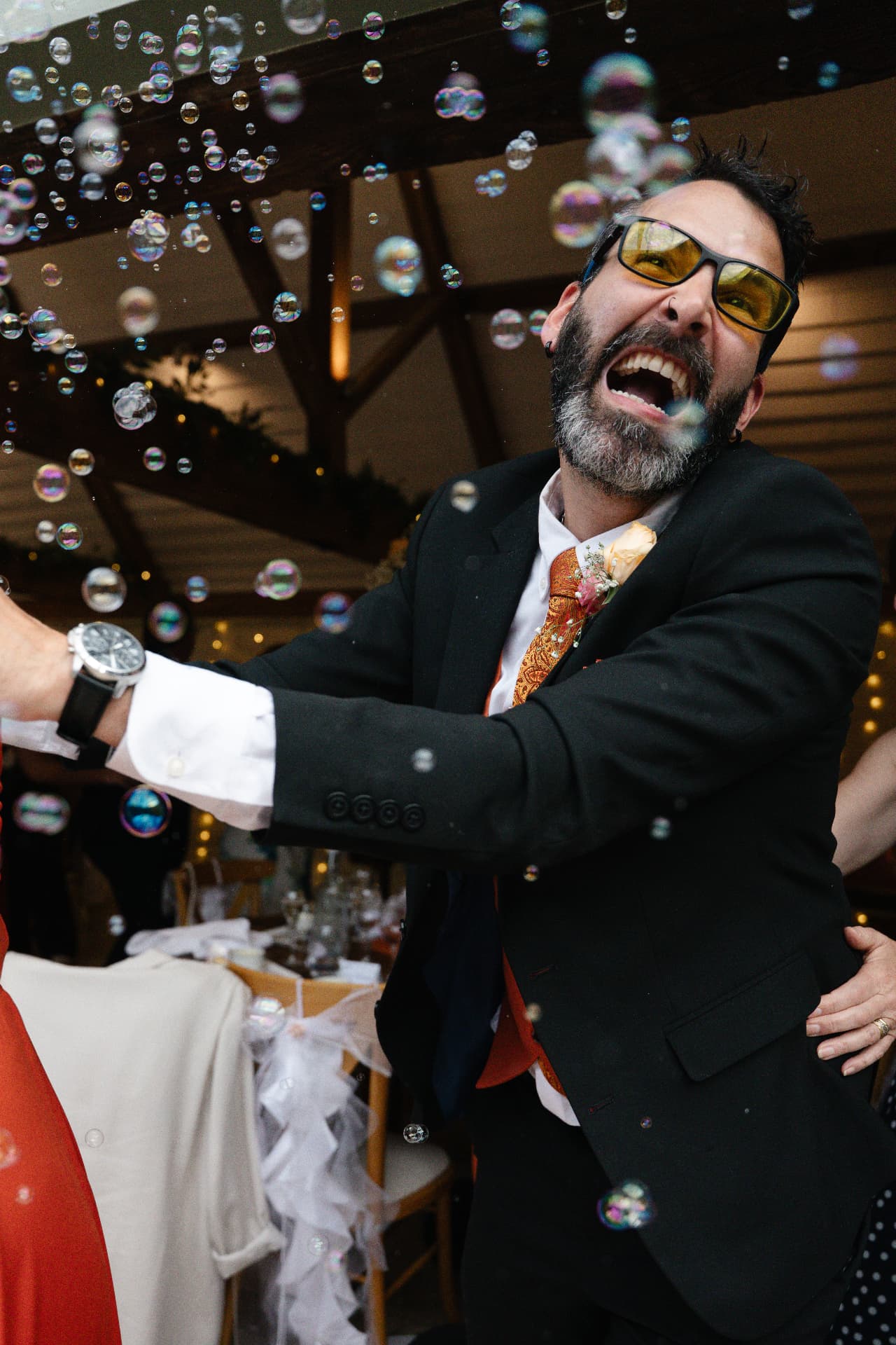 Wedding guest laughing surrounded by bubbles during the evening party, wedding photography Worcestershire & Midlands