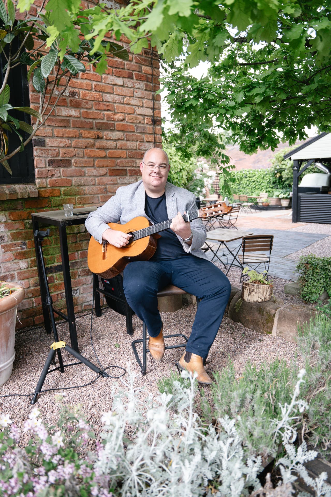 Musician playing acoustic guitar in a walled garden during the drinks reception, wedding photography Worcestershire & Midlands