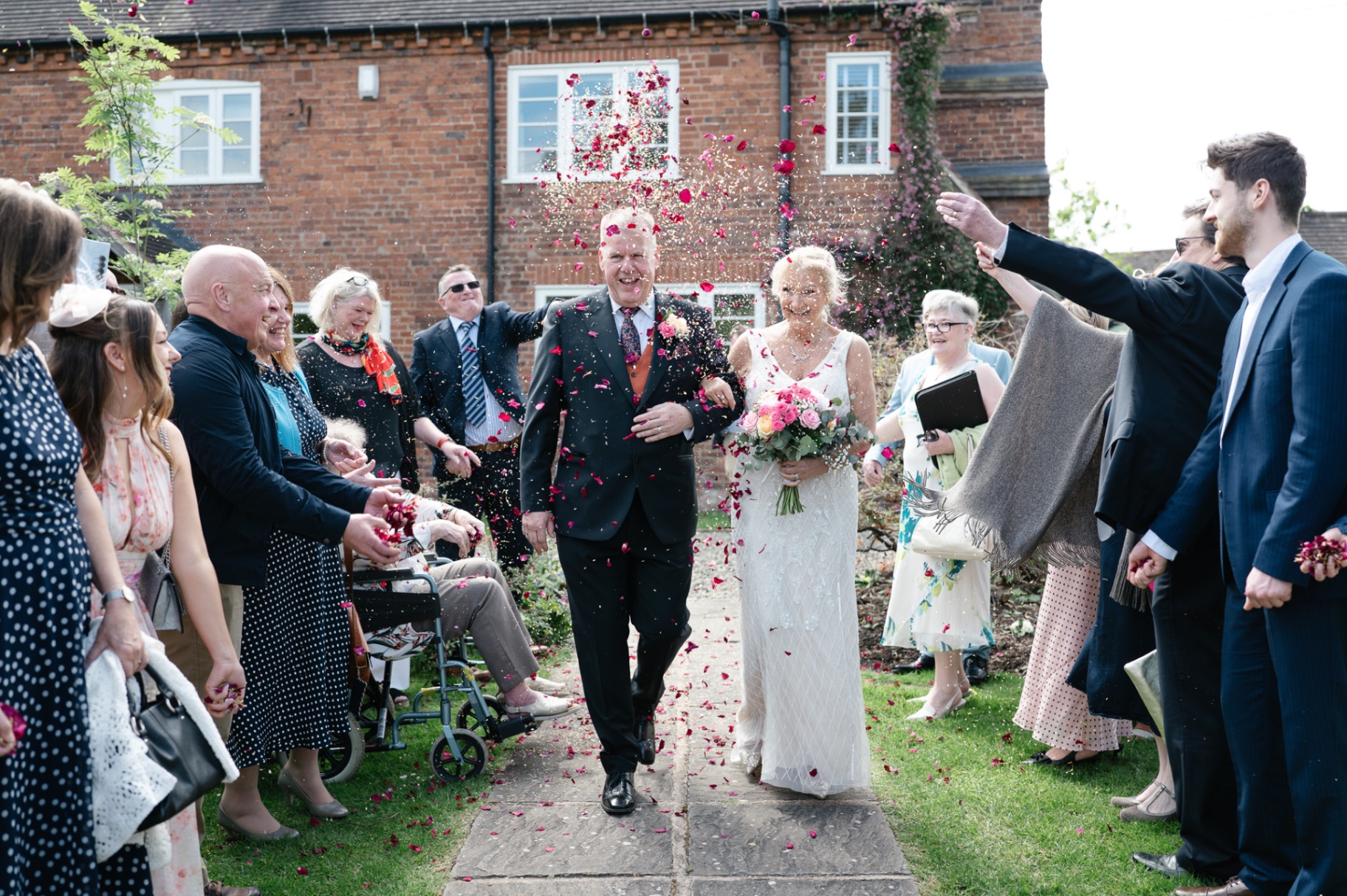 Bride and father walking through a shower of pink confetti at Curradine Barns